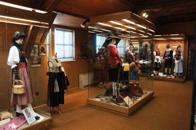 Austellungsraum mit verschieden Trachten die in Vitrinen ausgetellt sind