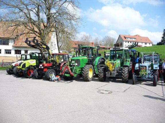 Verschiedene Traktoren im Bild vor einer Dorfkulisse